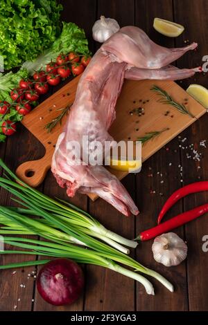 viande de lapin rouge fraîche sur une planche à découper en bois, vue latérale Banque D'Images