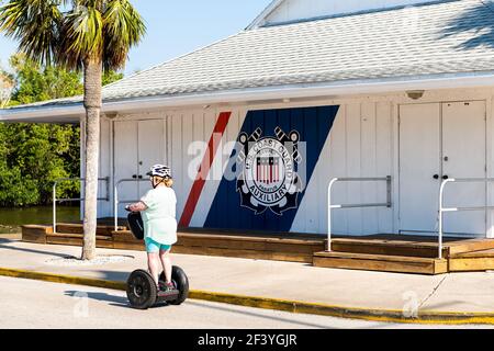 Naples, États-Unis - 30 avril 2018 : Floride golfe du mexique ville avec une femme en segway par la garde côtière américaine panneau de bâtiment auxiliaire pour la patrouille de la garde côtière Banque D'Images