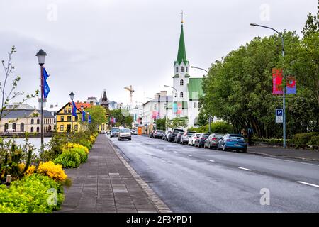 Reykjavik, Islande - 19 juin 2018 : route par le lac de Tjornin ou Reykjavikurtjorn dans la capitale du centre-ville, rue Frikirkjuvegur par temps nuageux Banque D'Images