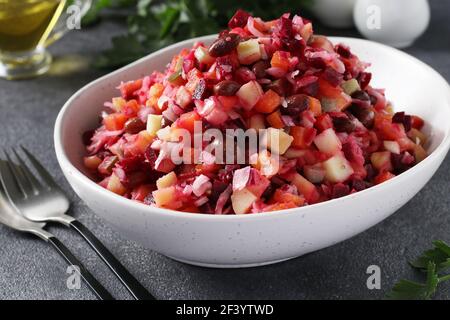 Salade traditionnelle vinaigrette de betteraves, pommes de terre, carottes, haricots, cornichons, oignons et huile végétale sur fond gris. Plats végétariens. Gros plan Banque D'Images