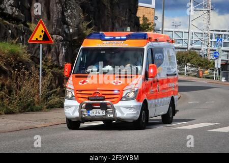 Véhicule d'urgence ambulancier en cas d'appel d'urgence roulant dans la rue pendant la journée. Détail : panneau de signalisation routière Falling Rocks. Helsinki, Finlande. 24 août 20. Banque D'Images