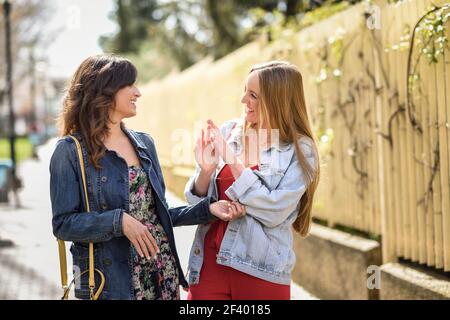 Deux jeunes femmes en milieu urbain. Concept de style de vie... Deux jeunes femmes heureuses qui parlent en milieu urbain. Concept de style de vie. Banque D'Images