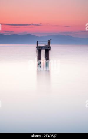 Structure des feux d'atterrissage de l'aéroport, dans la mer, au large de la côte de Corfou, Grèce.C'est tôt le matin et le soleil se lève sur l'eau très calme Banque D'Images