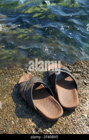 Une paire de sandales en cuir pour hommes sur le bord de l'eau et de la rsquo mer Banque D'Images