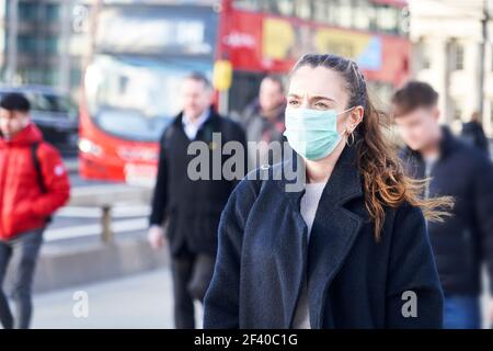 Jeune femme portant un masque de visage tout en marchant dans les rues de Londres Banque D'Images