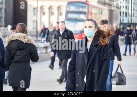 Jeune femme portant un masque de visage tout en marchant dans les rues de Londres Banque D'Images