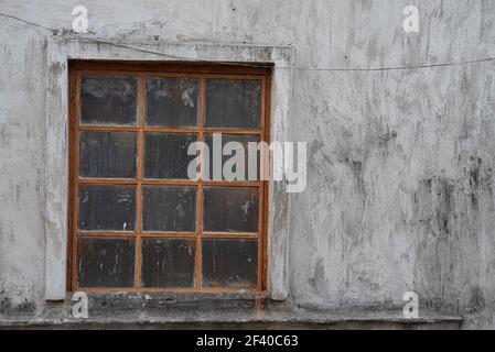 Une belle photo d'une vieille fenêtre avec des grilles, des taches et des fissures sur un mur de ciment Banque D'Images