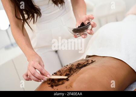 Femme nettoie la peau du corps avec Gommage au café spa centre de bien-être. Les concepts esthétiques et de beauté. Banque D'Images