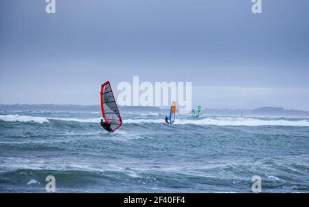 Planches à voile pendant une tempête d'hiver sur la plage de Rhosneigr, Anglesey, pays de Galles Banque D'Images