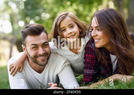 Une bonne famille dans un parc urbain. Père, mère et petite fille qui pond sur l'herbe. Une bonne famille dans un parc urbain Banque D'Images