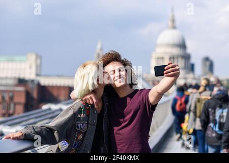 Couple heureux prenant une photo de selfie sur le Millennium Bridge de Londres&rsquo, sur la Tamise. Couple heureux prenant une photo de selfie sur le Millennium Bridge de Londres&rsco Banque D'Images