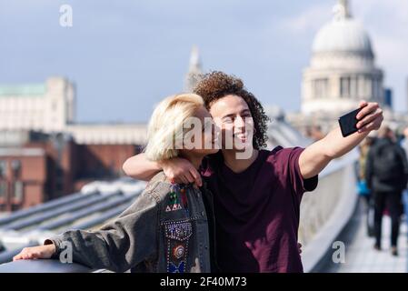 Couple heureux prenant une photo de selfie sur le Millennium Bridge de Londres&rsquo, sur la Tamise. Couple heureux prenant une photo de selfie sur le Millennium Bridge de Londres&rsco Banque D'Images