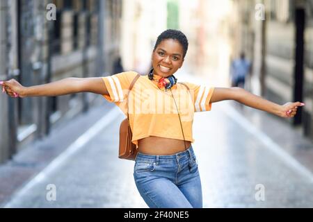 Une jeune femme noire danse dans la rue en été. Fille voyageant seule. Concept de style de vie... Une jeune femme noire danse dans la rue en été. Fille voyageant seule. Banque D'Images