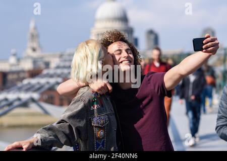 Couple heureux prenant une photo de selfie sur le Millennium Bridge de Londres&rsquo, sur la Tamise. Couple heureux prenant une photo de selfie sur le Millennium Bridge de Londres&rsco Banque D'Images