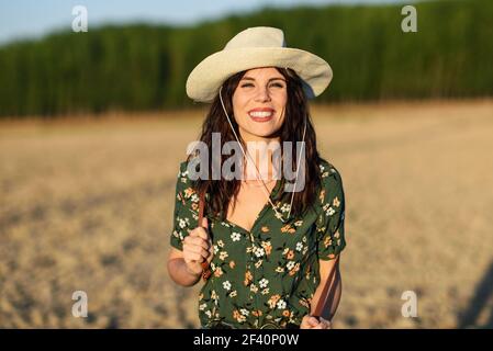 Belle jeune femme de randonnée, portant une chemise fleurie, un chapeau de soleil et un short en denim, randonnée à la campagne. Randonneurs jeunes femmes randonnée dans la campagne au coucher du soleil Banque D'Images