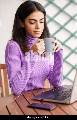 Femme persane assise dans un fauteuil sur son balcon à l'aide d'un ordinateur portable. Femme persane sur son balcon en utilisant un ordinateur portable Banque D'Images