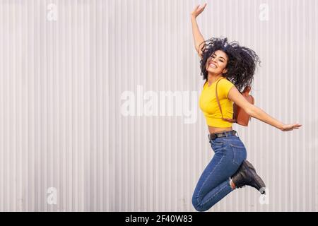 Bonne femme arabe sautant en milieu urbain. Afro cheveux femme.. Bonne femme arabe sautant en milieu urbain. Banque D'Images