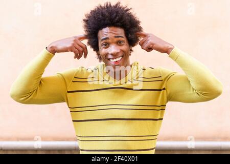 Homme noir aux cheveux afro mettant une expression folle à l'extérieur. Homme noir aux cheveux afro mettant une expression folle Banque D'Images