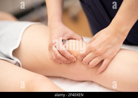 Femme kinésithérapeute femme qui fait un traitement sur une jeune femme et un genou... Femme physiothérapeute qui fait un traitement sur un genou de femme et de rsquo. Banque D'Images