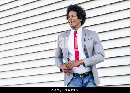 Joyeux homme d'affaires noir vêtu d'un costume dansant à l'extérieur. Homme avec cheveux afro.. Joyeux homme d'affaires noir vêtu d'un costume dansant à l'extérieur. Banque D'Images