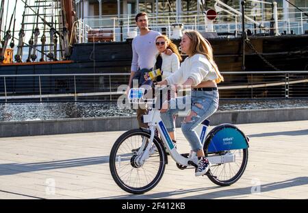 Dundee, Tayside, Écosse, Royaume-Uni. 18 mars 2021. Météo au Royaume-Uni : soleil de printemps chaud dans le nord-est de l'Écosse avec des températures atteignant 17°C. Une jeune femme en plein air passe du temps en fin d'après-midi à monter à bord d'une ville. Elle embarque un vélo électrique devant le bateau RRS Discovery, le long du front de mer de Dundee, pendant le lockdown de niveau 4 Covid-19. Crédit : Dundee Photographics/Alamy Live News Banque D'Images