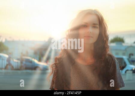 Flou portrait flou de femme mignonne en coucher de soleil rayons de soleil image rétro-éclairée. Flou doux portrait flou de femme mignonne dans les rayons du soleil du coucher du soleil Banque D'Images