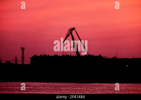 Silhouette de la grue de port devant le ciel rouge de coucher de soleil, beaucoup d'espace publicitaire sur le ciel. Silhouette de la grue du port devant Red Sunset Sky Banque D'Images