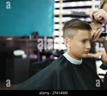 Un garçon obtient une coupe de cheveux élégante dans un salon de coiffure Banque D'Images