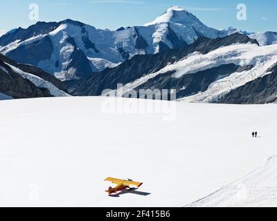 Suisse Jungfraujoch-Haut de l'Europe. Avion sur glacier avec montagnes en arrière-plan et deux personnes à pied. Le Grand glacier d'Aletsch. Banque D'Images