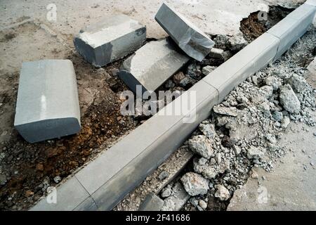 Réparation d'une bordure de route asphaltée. Des tas de pierres à bordure couchés sur le trottoir près de la fosse pour l'installation d'une bordure. Surface d'asphalte cassée de l'autre côté. Un trou dans la surface de la route. Réparation de travaux routiers. Réparation d'une bordure de route asphaltée. Des tas de pierres à bordure couchés sur le trottoir près de la fosse pour l'installation d'une bordure. Banque D'Images