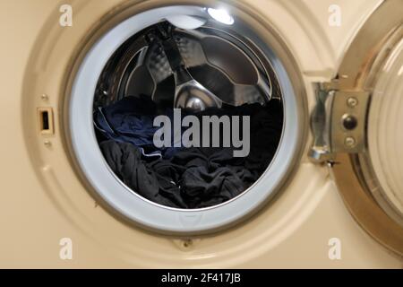 Gros plan du lave-linge ouvert avec des vêtements sales à l'intérieur du tambour Banque D'Images