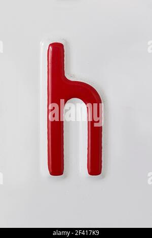 Lettre h rouge en relief sur une plaque en étain blanc Banque D'Images