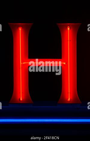 Lettre H lumineuse rouge la nuit avec soulignement bleu Banque D'Images