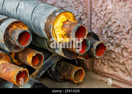 Réparation de canalisations d'eau. Tuyau en acier rouillé avec isolation sur le site de construction dans un emballage en mousse plastique pour tube allongé sur la cour en tas horizontalement. Vieux pipeline rouillé empilé près du mur. Réparation de canalisations d'eau. Tuyau en acier rouillé avec isolation sur le site de construction dans un emballage en plastique de tube allongé sur la cour dans un tas horizontal. Vieux pipeline rouillé empilé Banque D'Images