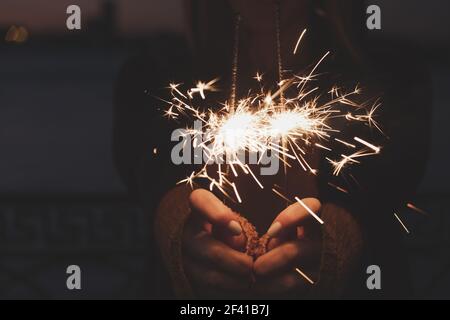 Mains de femmes tenant deux étincelles en feu devant la partie centrale du corps. Les mains des femmes tiennent deux étincelles brûlantes Banque D'Images