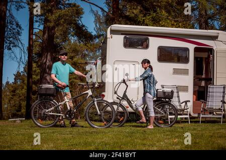 Femme avec un homme en vélo électrique reposant sur le camping. Vacances famille vacances, voyages voyage en camping-car, caravane RV Location vacances. Banque D'Images