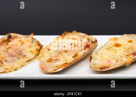 (machas a la parmesana) seashell cuit au parmesan. servi sur une assiette blanche Banque D'Images