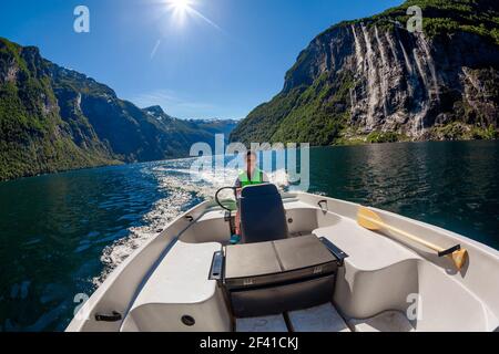 Femme conduisant un bateau à moteur sept Sœurs cascade sur le fond. Fjord Geiranger, belle nature Norvège. Le fjord Geiranger, site classé au patrimoine mondial de l'UNESCO Banque D'Images