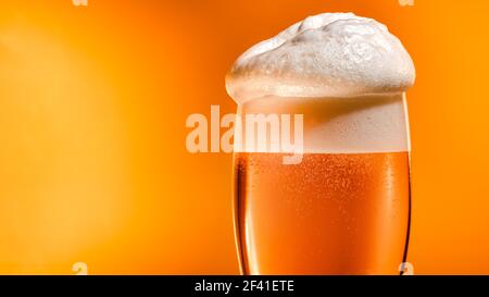 La bière lager s'installe dans le verre avec un bouchon blanc en mousse Banque D'Images