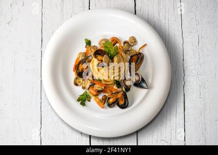 pâtes de fruits de mer, spaghetti italiens aux palourdes moules et persil dans la plaque blanche sur des planches de bois de couleur blanche, plan d'appartement avec vue sur le dessus Banque D'Images