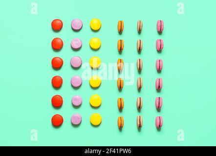 Biscuits aux macarons aux amandes multicolores, sur fond vert, vue du dessus. Plusieurs macarons symétriques alignés. Petits gâteaux français avec meringue sans gluten. Banque D'Images