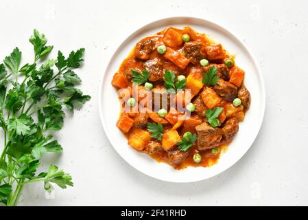 Ragoût de bœuf maison avec pommes de terre et carottes à la sauce tomate. Vue de dessus, plan d'appartement Banque D'Images