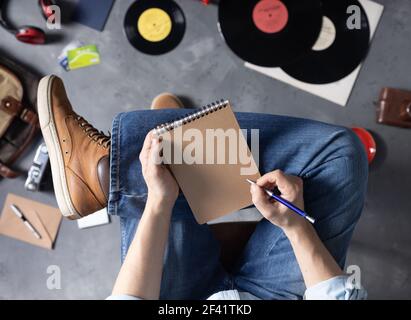 Main pour homme tenant un stylo ou un crayon et un cahier et une jambe en Jean. Concept de style de vie pour l'étude ou l'art de la musique Banque D'Images