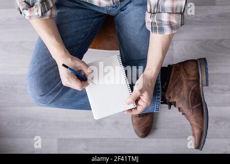 Main pour homme tenant un crayon et un carnet. Étudiant homme écriture ou dessin à la main au crayon, vue de dessus Banque D'Images