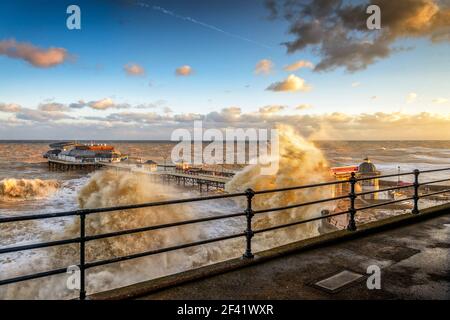 Des mers agitées battent la côte nord de Norfolk, avec des vagues qui se brisent sur la promenade et l'ancienne jetée victorienne à la station de vacances de Cromer Banque D'Images