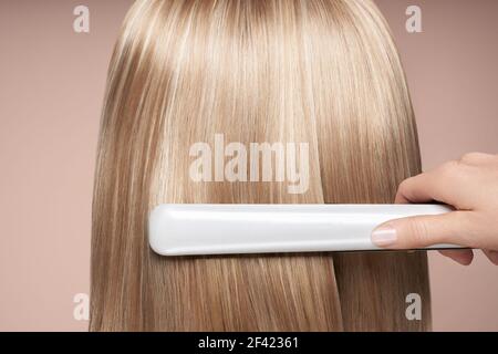 Coiffure le redressage de longs cheveux noirs avec des fers de cheveux. Belle femme avec de longs cheveux raides. Coiffure lisse Banque D'Images