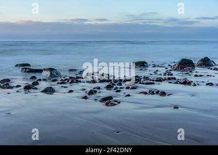 sur la rive de l'eau grandes et petites pierres lavées à l'eau et des nuages à l'horizon Banque D'Images