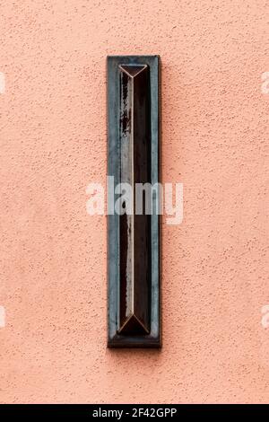 Lettre I marron foncé émaillée sur un mur orange vif Banque D'Images