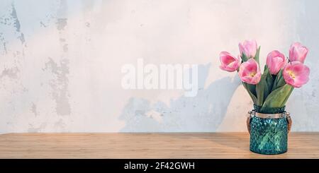 Tulipes roses dans vase vert sur table en bois au soleil de la fenêtre Banque D'Images