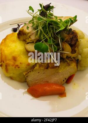 Filet de poulet cuit avec une casserole de pommes de terre, garni d'herbes et de légumes Banque D'Images